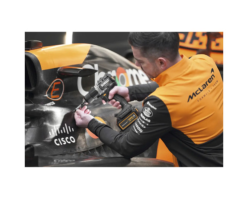 Muž pracuje s akumulátorovou vrtačkou Dewalt na závodním autě.