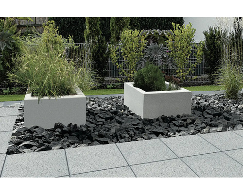 Zahradní scéna se dvěma osázenými, čtvercovými kamennými květináči obklopenými ozdobnými kameny na kamenných deskách.