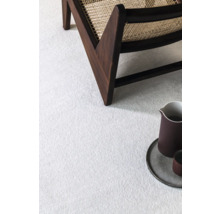 Detailní pohled na světlý koberec se židlí a dekorací