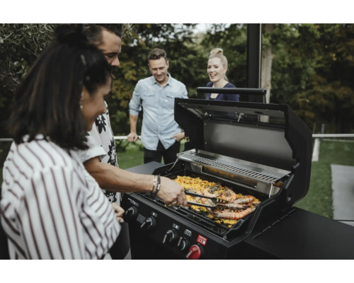 Skupina lidí griluje krevety na plynovém grilu venku