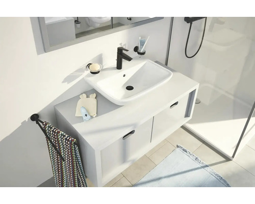 Moderní koupelna s bílým umyvadlem, černou baterií a držákem na ručníky.