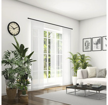 Světlý obývací pokoj s pohovkou, konferenčním stolkem, pokojovými rostlinami, hodinami a posuvným závěsem před oknem.