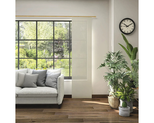 Obývací pokoj s pohovkou, pokojovými rostlinami, hodinami a posuvným panelem před oknem