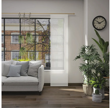 Obývací pokoj s pohovkou, pokojovými rostlinami, hodinami a posuvným panelem před oknem