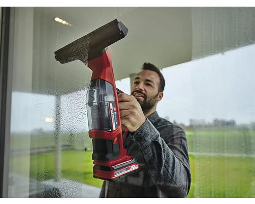 Muž čistí okna pomocí akumulátorového čističe oken.