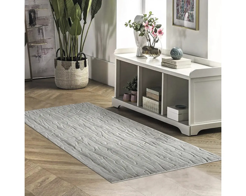 Šedý koberec se vzorem ve světlé místnosti s komodou a pokojovými rostlinami