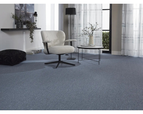 Obývací pokoj s modrým kobercem, křeslem a odkládacím stolkem