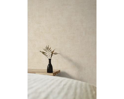 Dekorativní váza s větví rostliny na dřevěném stole před strukturovanou zdí.