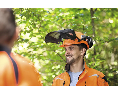 Lesník s lesnickou helmou s hledím a chrániči sluchu od společnosti Stihl