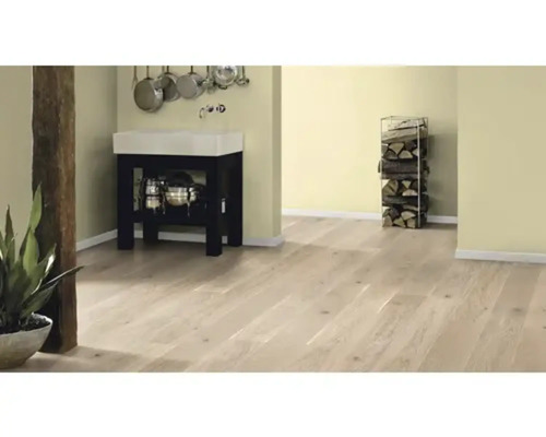 Světlá místnost s dřevěnou podlahou, umyvadlem a skladem dřeva