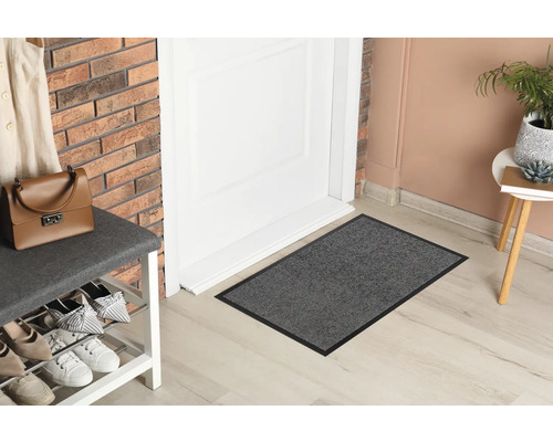 Scéna s rohožkou před dveřmi, botníkem a dekorativními předměty.