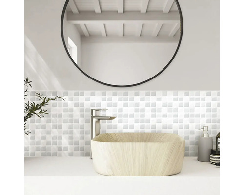 Koupelna s umyvadlem, baterií, mozaikovými obklady a kulatým zrcadlem