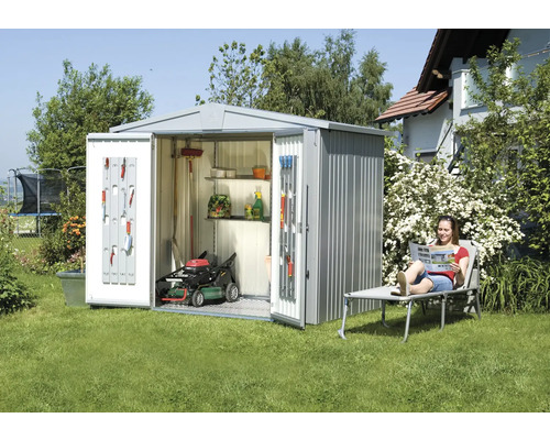 Kovová bouda na nářadí s otevřenými dveřmi, sekačkou na trávu a zahradním nářadím na zahradě.