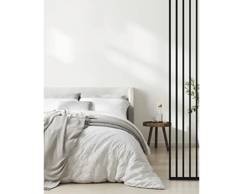 Světlá ložnice s postelí, nočním stolkem a děličem místnosti