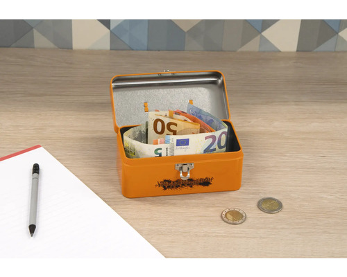 Otevřený oranžový kovový box s euronovkami, mincemi, perem a poznámkovým blokem na stole.