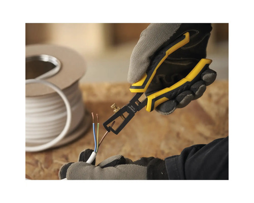 Osoba používá odizolovací kleště na kabelu. V pozadí je cívka kabelu.