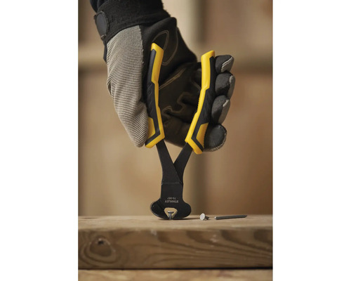 Ruka v pracovních rukavicích drží štípací kleště nad dřevěnou deskou, na které leží hřebíky.