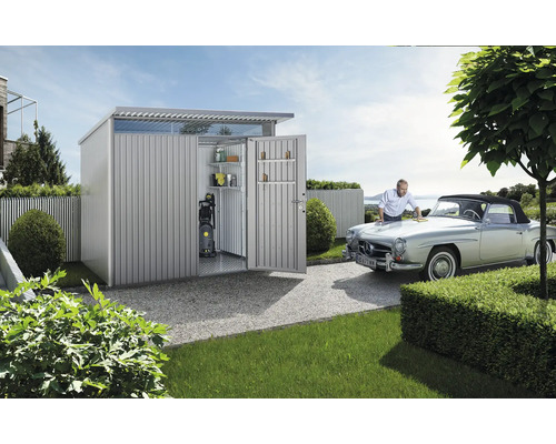 Kovový zahradní domek s otevřenými dveřmi a muž leštící auto