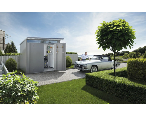 Zahradní scéna s zahradním domkem, veteránem a mužem pečujícím o auto