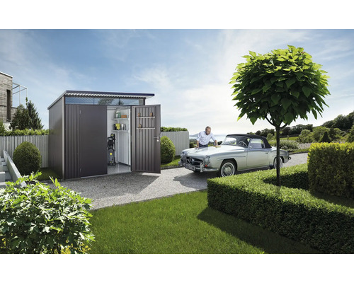 Zahradní scéna s kovovým zahradním domkem s policemi a tlakovou myčkou, muž čistí veterána