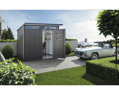 Kovová kůlna s otevřenými dveřmi, policemi, vysokotlakým čističem a mužem leštícím auto