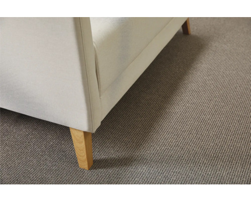 Detail béžového koberce pod pohovkou s dřevěnými nohami