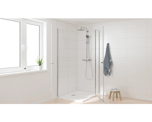 Světlá koupelna se sprchou, sprchovou hlavicí, ručníkem a oknem pro přátelské prostředí.