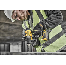 Řemeslník vrtá žlutou akumulátorovou vrtačkou DeWalt do kusu kovu.