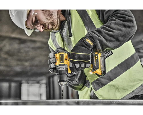 Řemeslník vrtá žlutou akumulátorovou vrtačkou DeWalt do kusu kovu.