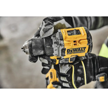 Detail akumulátorové vrtačky DeWalt v ruce řemeslníka v pracovních rukavicích