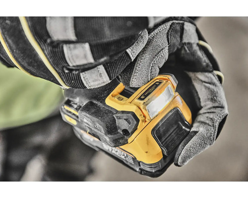 Ruce v pracovních rukavicích drží žluté pracovní světlo