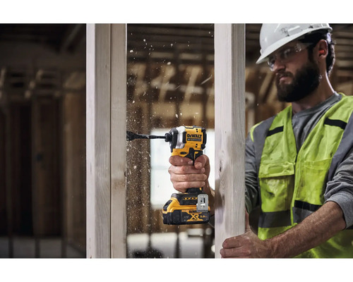 Řemeslník vrtá otvor do dřevěné desky pomocí akumulátorového rázového utahováku.