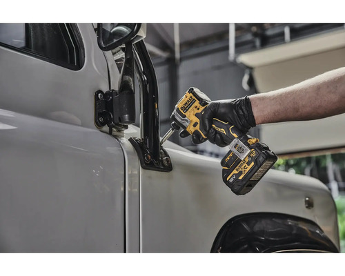 Muž připevňuje vnější zrcátko na auto pomocí akumulátorového rázového utahováku.