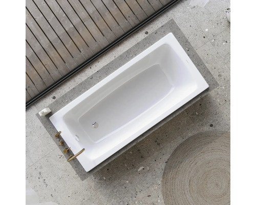 Pohled shora na obdélníkovou bílou vanu s bateriemi na šedém pozadí