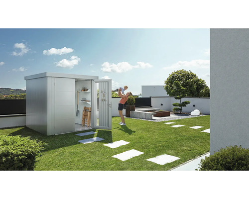 Zahradní scéna s domkem na nářadí, trávníkem a hrající si matkou s dítětem