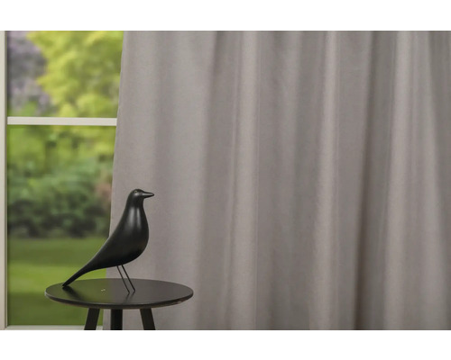 Dekorace s ptákem na stole před oknem se závěsem