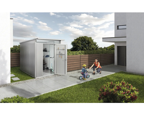 Kovový zahradní domek s otevřenými dveřmi, dítě na kole a matka na zahradě