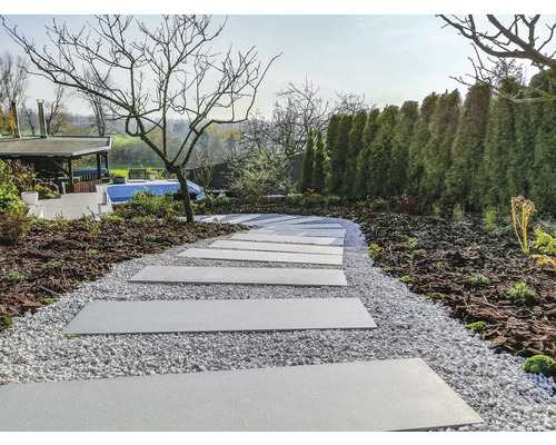 Zahradní scéna s chodníkovými deskami a štěrkovou cestou mezi zahradními rostlinami