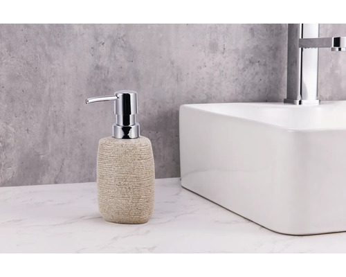 Dávkovač mýdla se vzhledem kamene s chromovanou pumpičkou vedle umyvadla