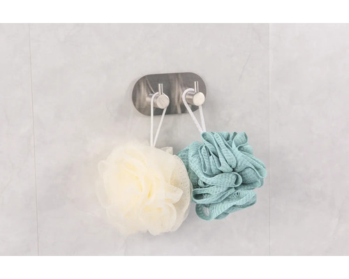 Dvě sprchové houby visí na háku pro uložení v koupelně.