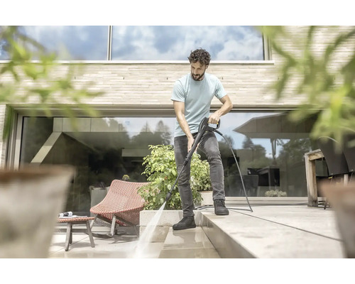 Muž čistí terasu vysokotlakým čističem