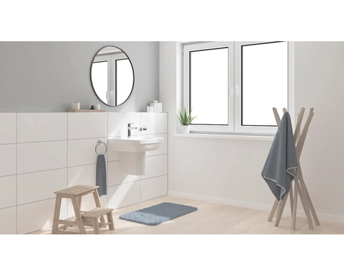 Světlá koupelna s umyvadlem, zrcadlem, držákem na ručníky a koupelnovou předložkou