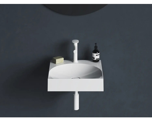 Bílé umyvadlo na stěnu s baterií, mýdlem a dávkovačem mýdla