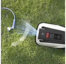 Pohled shora na robotickou sekačku a zahradní hadici na trávníku.