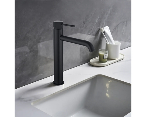 Černá umyvadlová baterie vedle umyvadla a koupelnových potřeb na umyvadle