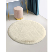 Bílý kulatý koberec se stoličkou a stolem v pozadí