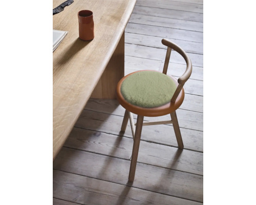 Dřevěná stolička s kulatým sedákem a opěradlem vedle stolu.