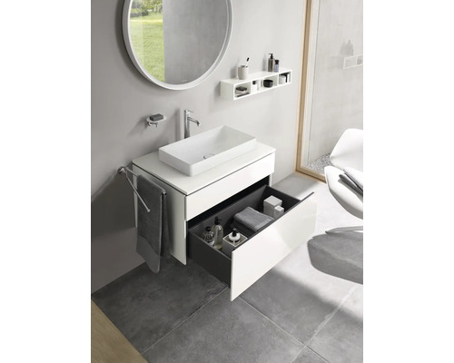 Moderní koupelna s umyvadlem, zrcadlem, policí a otevřeným zásuvkovým prvkem.