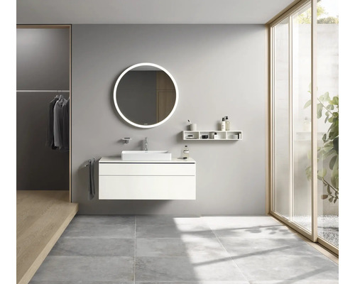 Koupelna s umyvadlem, kulatým zrcadlem s osvětlením a policemi.