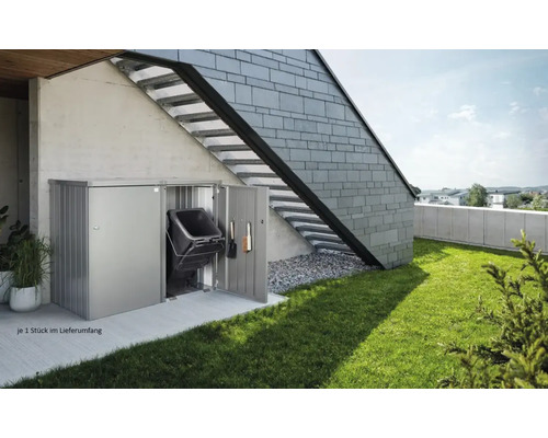 Kovový box na popelnice s popelnicí a zahradním nářadím u stěny domu s venkovním schodištěm